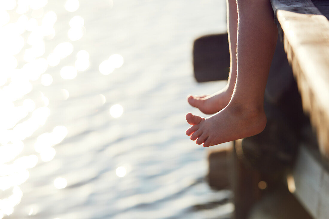 Person, die auf einem Pier über einem See sitzt