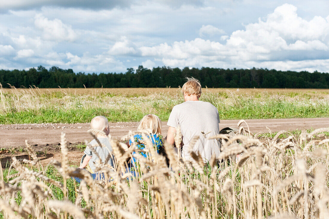 Father with children sitting near field