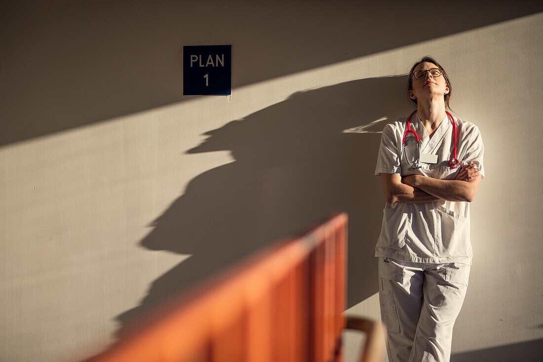 Female doctor standing by wall