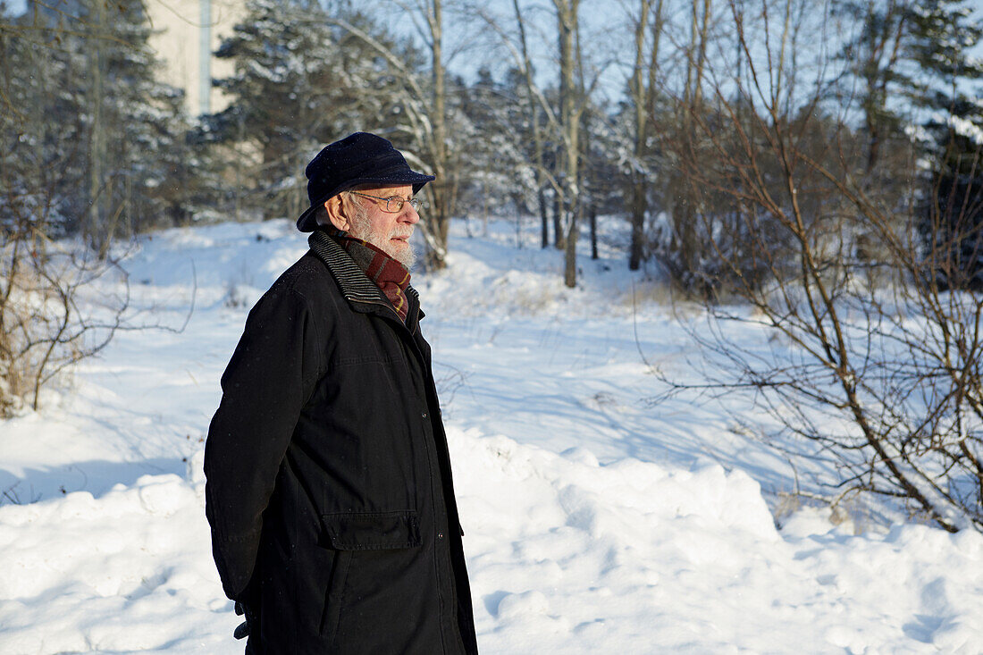 Älterer Mann geht im Winter im Wald spazieren