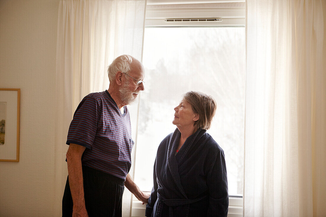 Älteres Paar steht neben einem Fenster