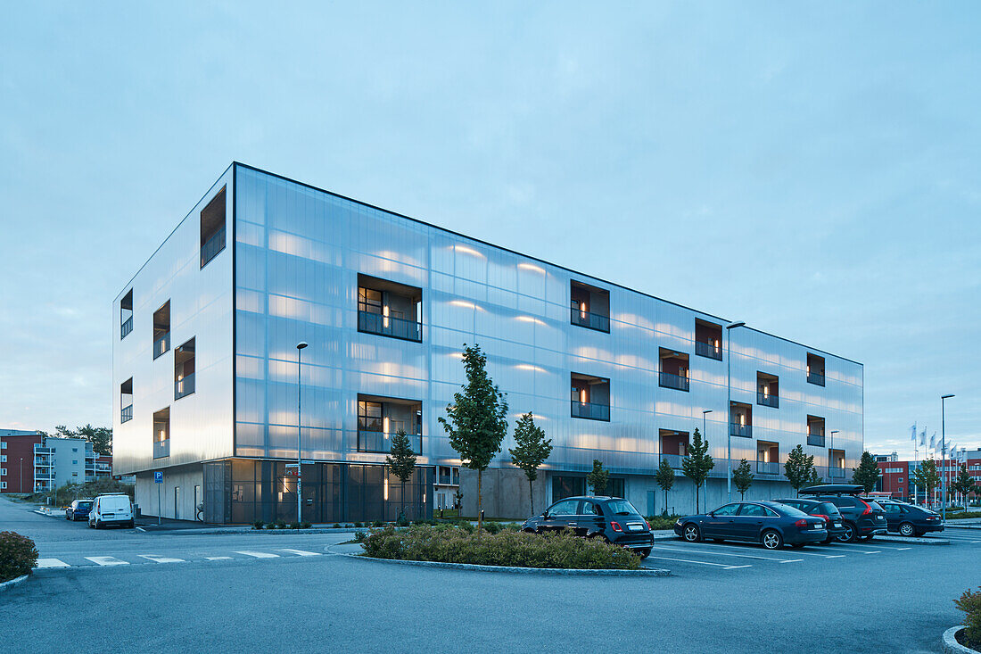 Modernes Wohngebäude und Parkplatz in der Abenddämmerung