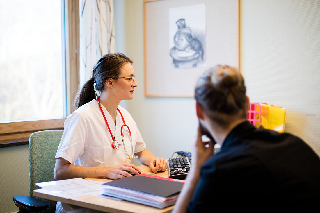 Arzt und Patientin sitzen im Büro