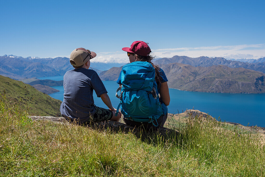 Junge mit Frau schaut auf einen See in den Bergen