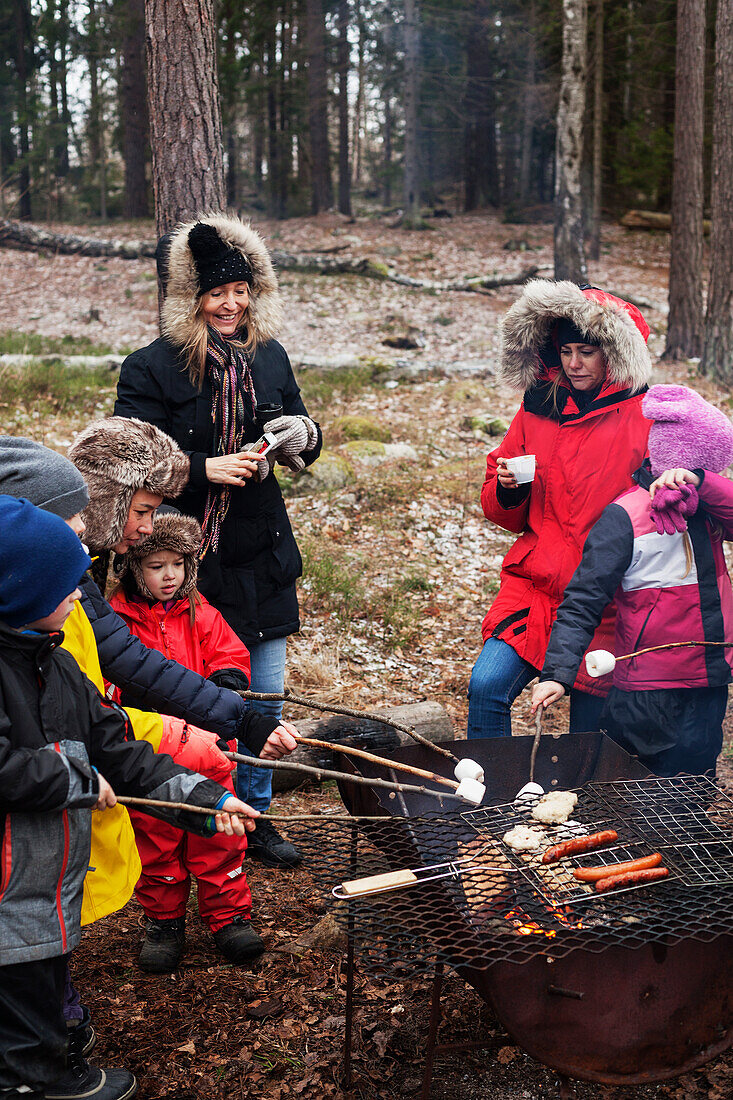 Women with children preparing barbecue in forest