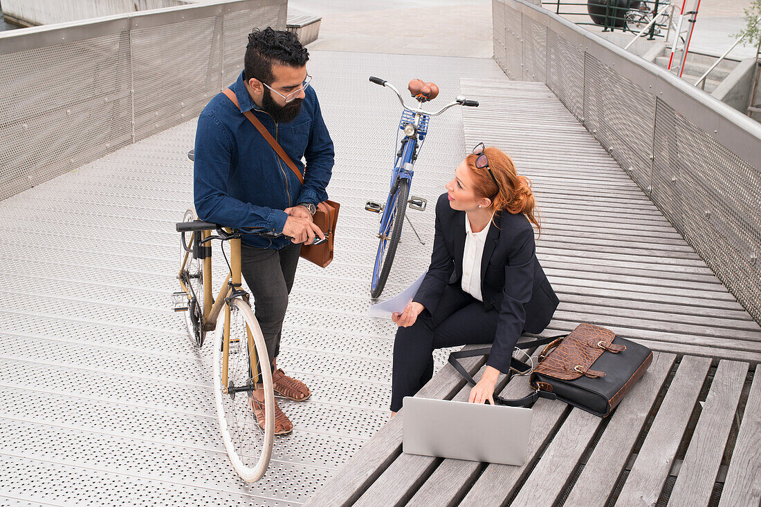 Man and woman using laptop outdoors