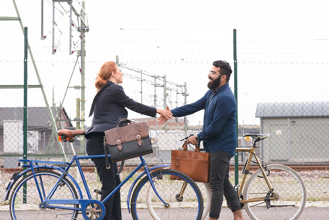 Man and woman shaking hands on street