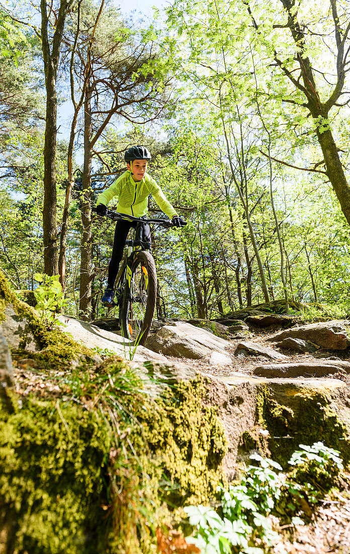 Boy cycling through forest