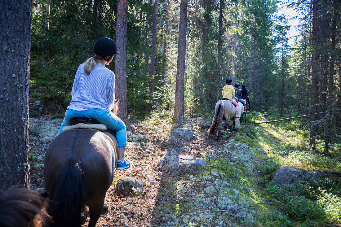 Children horse riding through forest