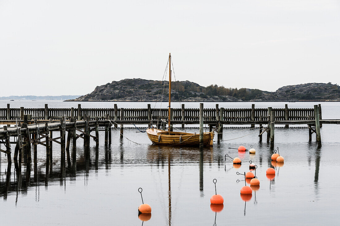 Sailing boat moored at jetty, buoys on foreground