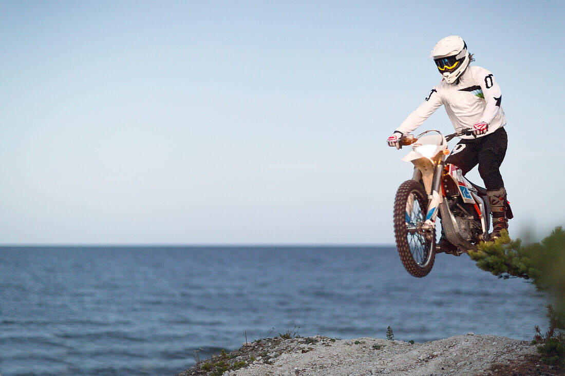 Mann springt auf Motorrad am Strand