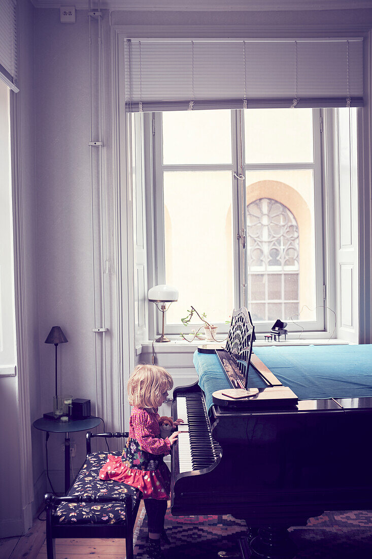 Little girl playing piano in living room