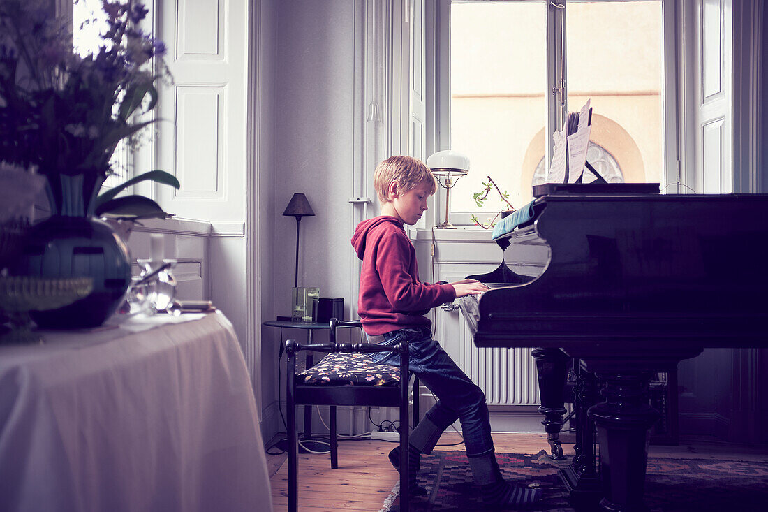 Junge spielt Klavier im Wohnzimmer