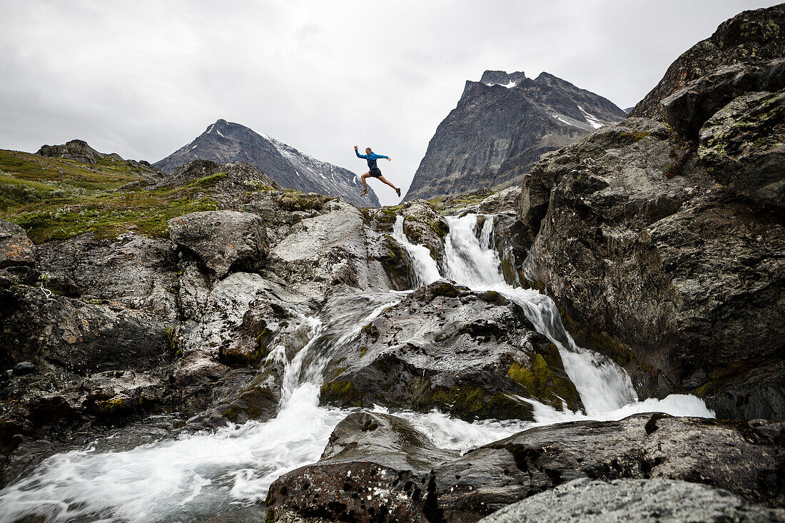 Person springt über Bergfluss