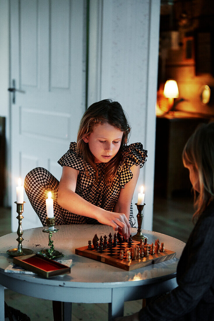 Zwei Mädchen spielen Schach im Wohnzimmer