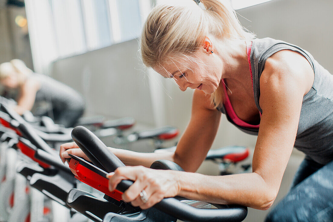 Woman exercising on stationary bicycle in gym