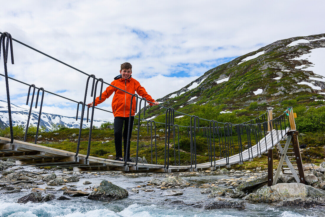 Boy walking on footbridge above river