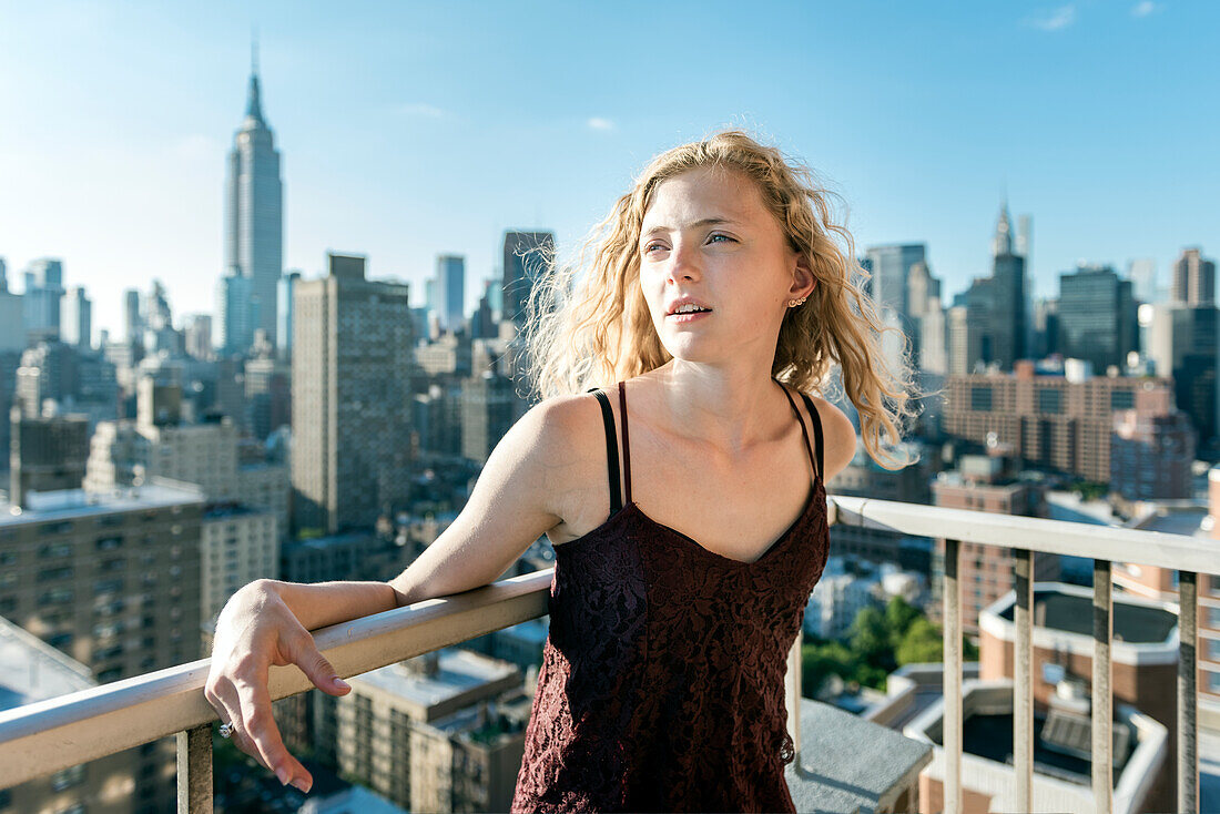 Blonde Frau steht vor einem Wolkenkratzer
