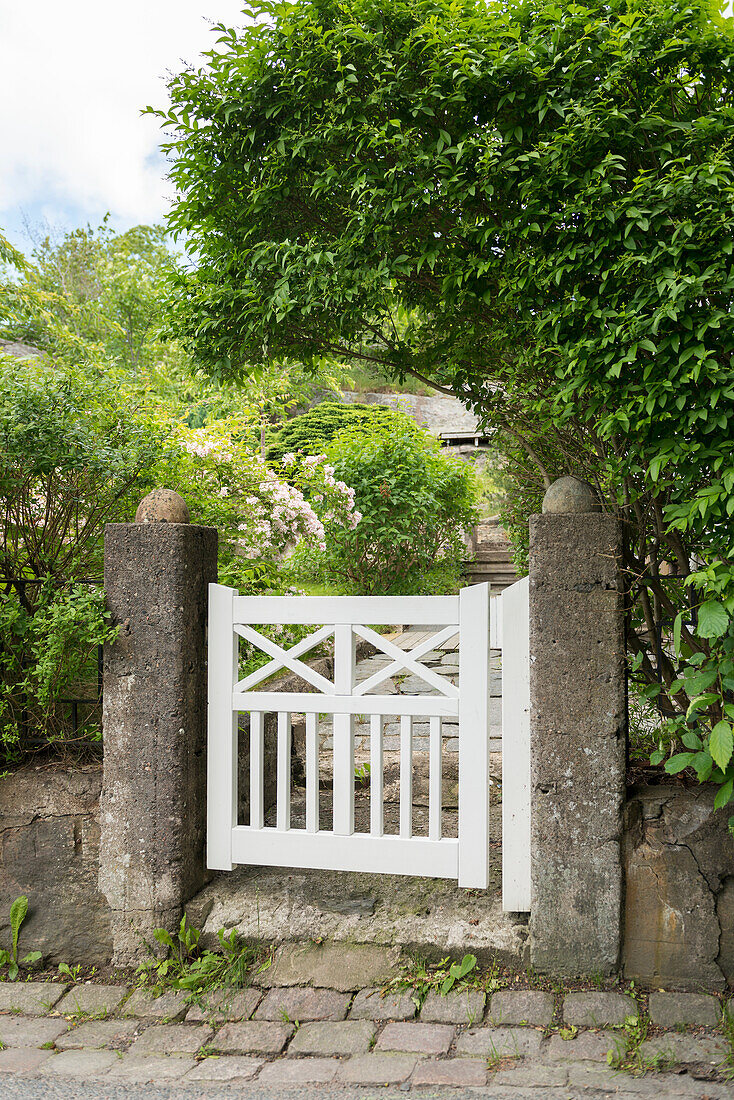 Kleines weißes Tor, das zum Garten führt