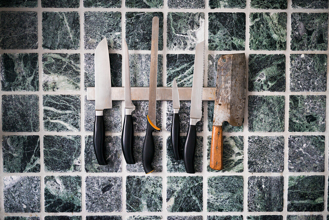 Kitchen knives against tiled wall