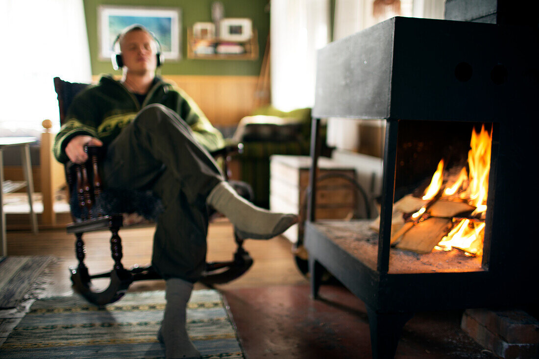 Man listening to music next to fireplace