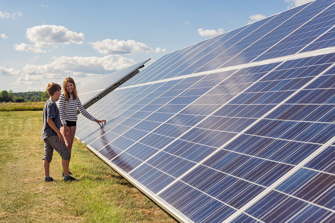 Boy and girl standing next to solar panels