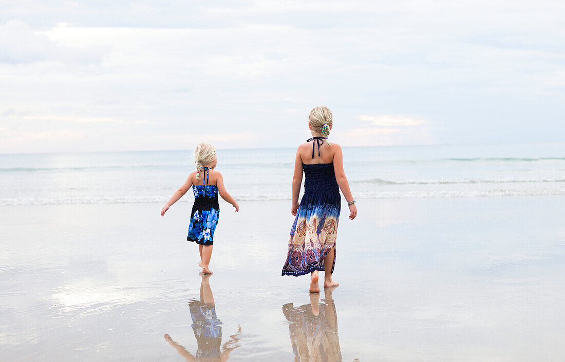 Mutter und Tochter spazieren am Strand