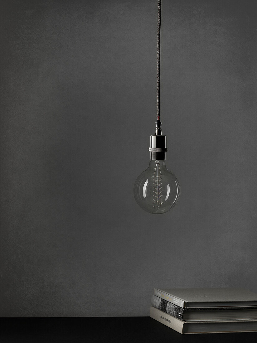 Light bulb hanging against grey background