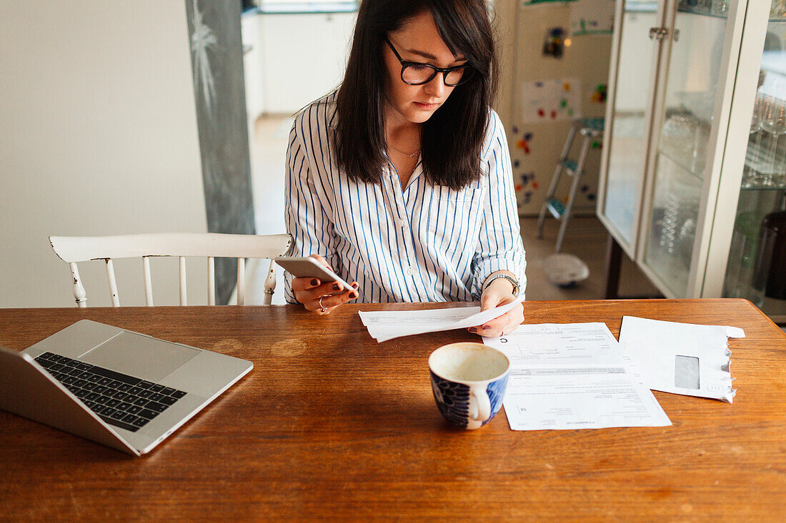 Woman with laptop and smartphone in dining room