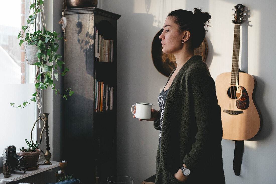 Junge Frau hält Becher im Zimmer