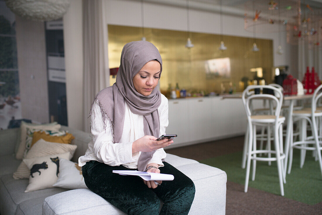 Junge Frau mit Smartphone im Büro