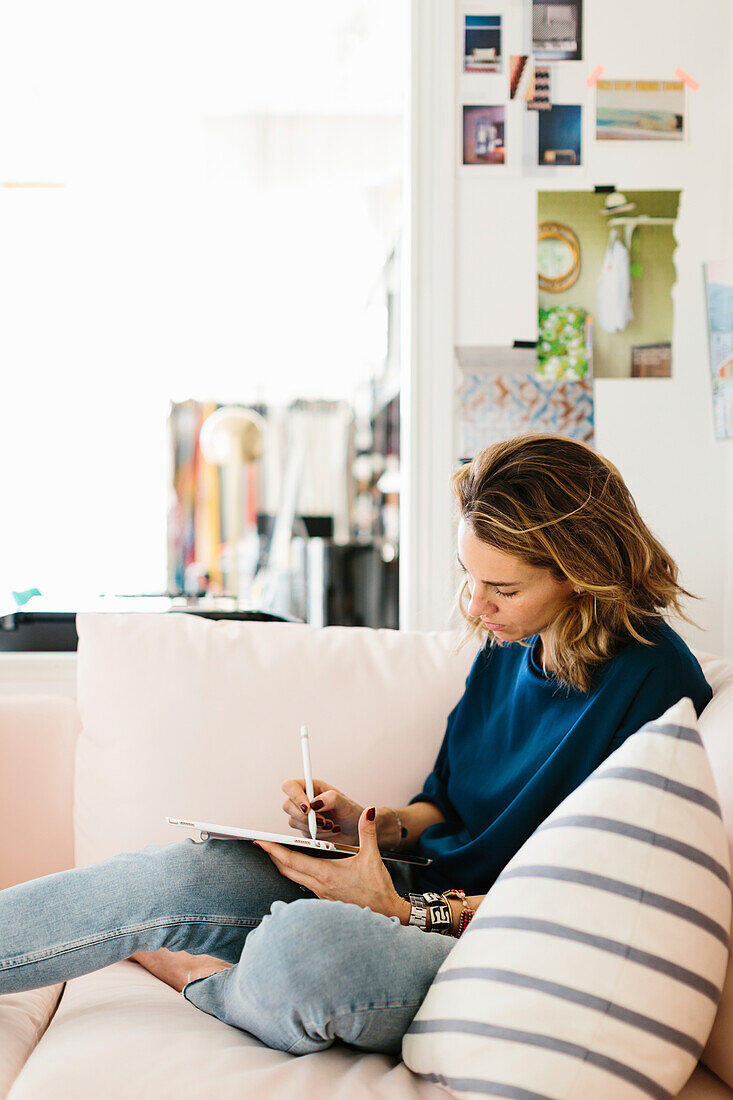 Frau sitzt auf dem Sofa und benutzt ein Tablet