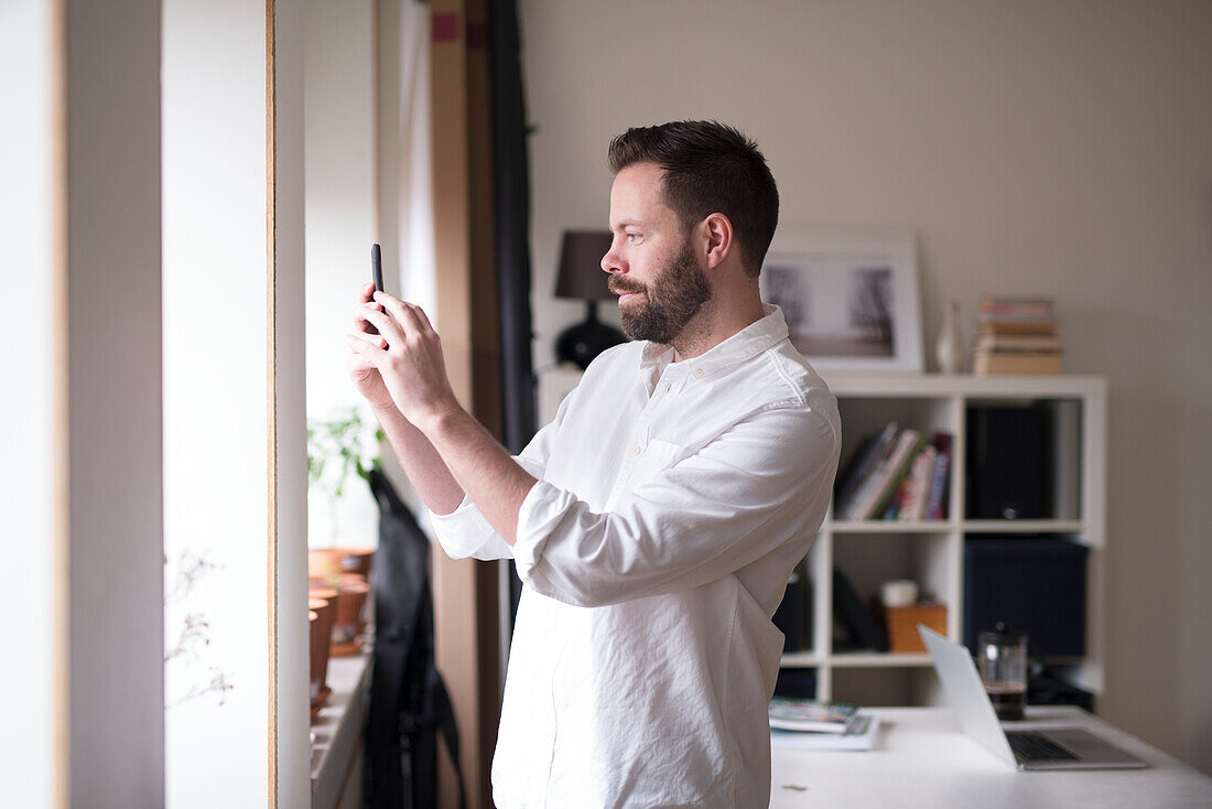 Mann fotografiert mit Mobiltelefon