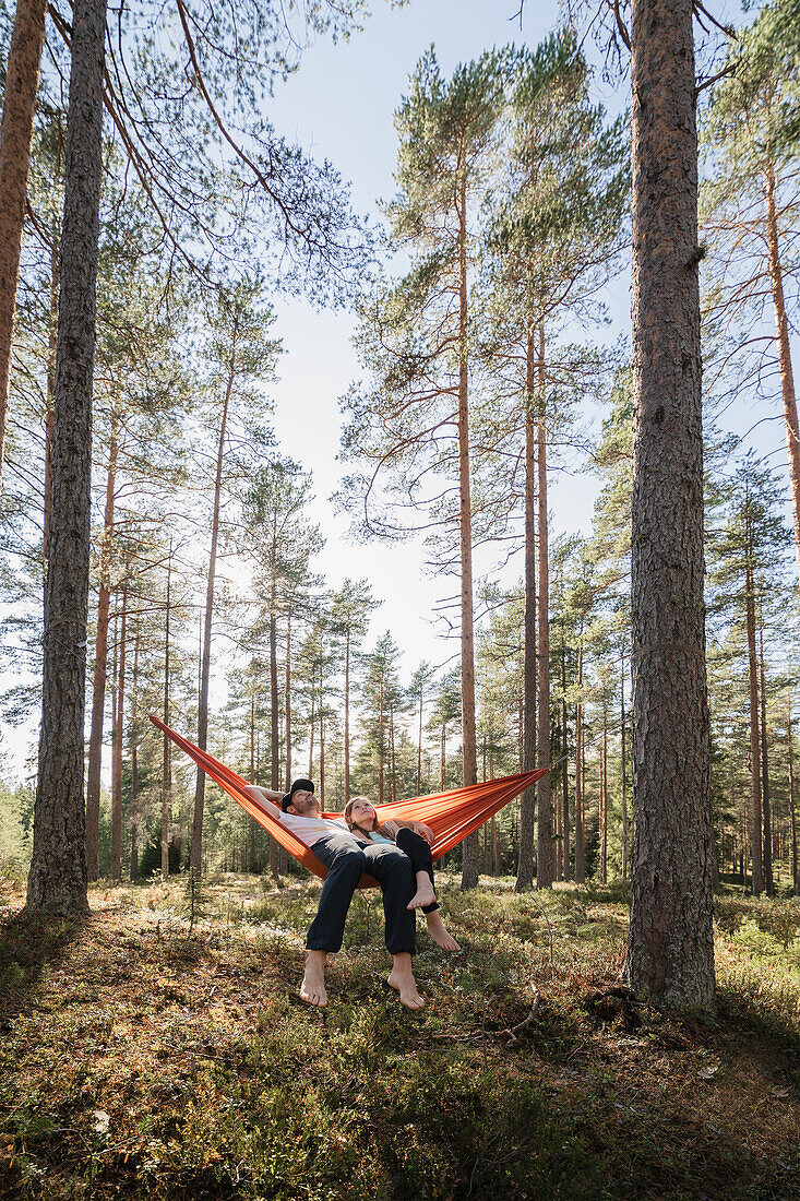 Junges Paar liegt in Hängematte im Wald