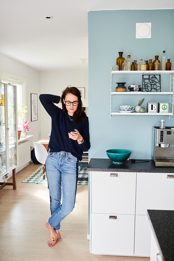 Woman using smartphone in kitchen