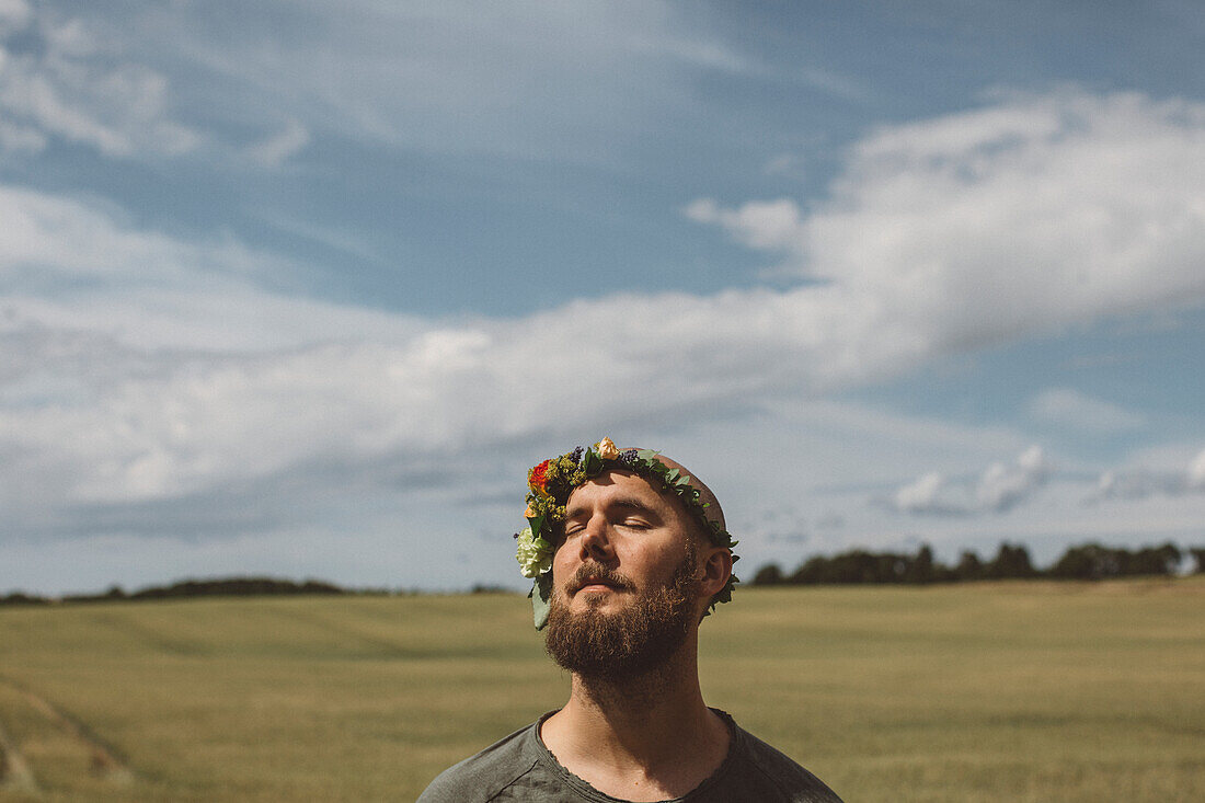 Mann trägt Blumenkranz