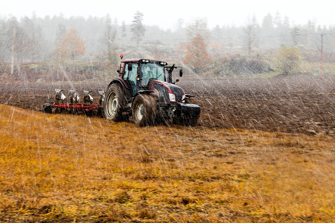 Tractor plowing field in rain
