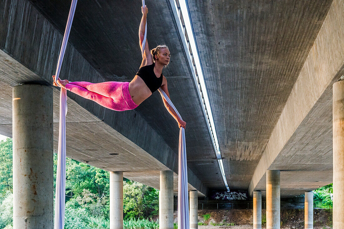 Woman doing acrobatics under concrete structure