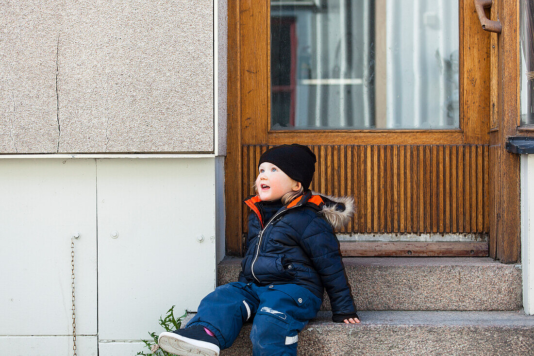 Junge sitzt auf der Türtreppe