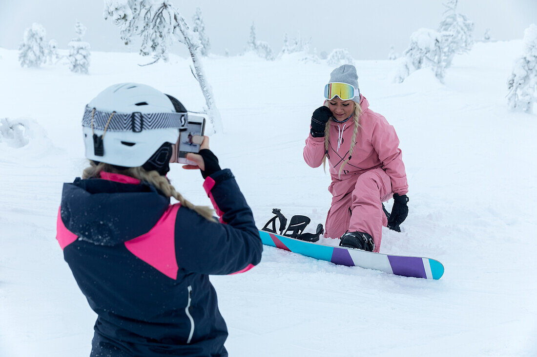 Women taking picture while snowboarding