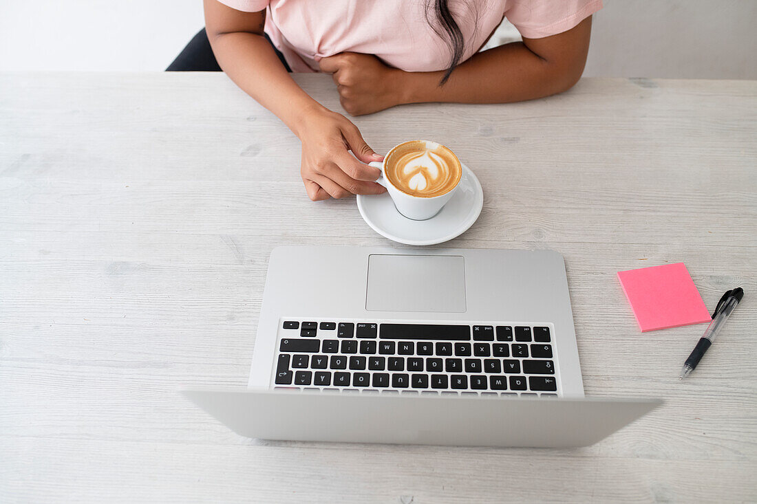 Woman having coffee in front of laptop