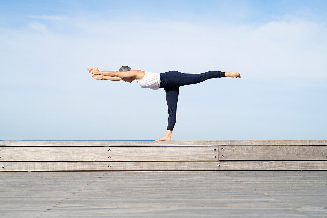 Woman practicing yoga on pier