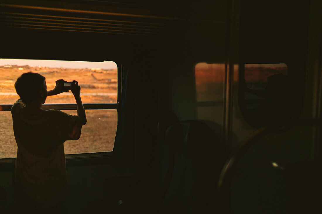 Boy taking picture through train window