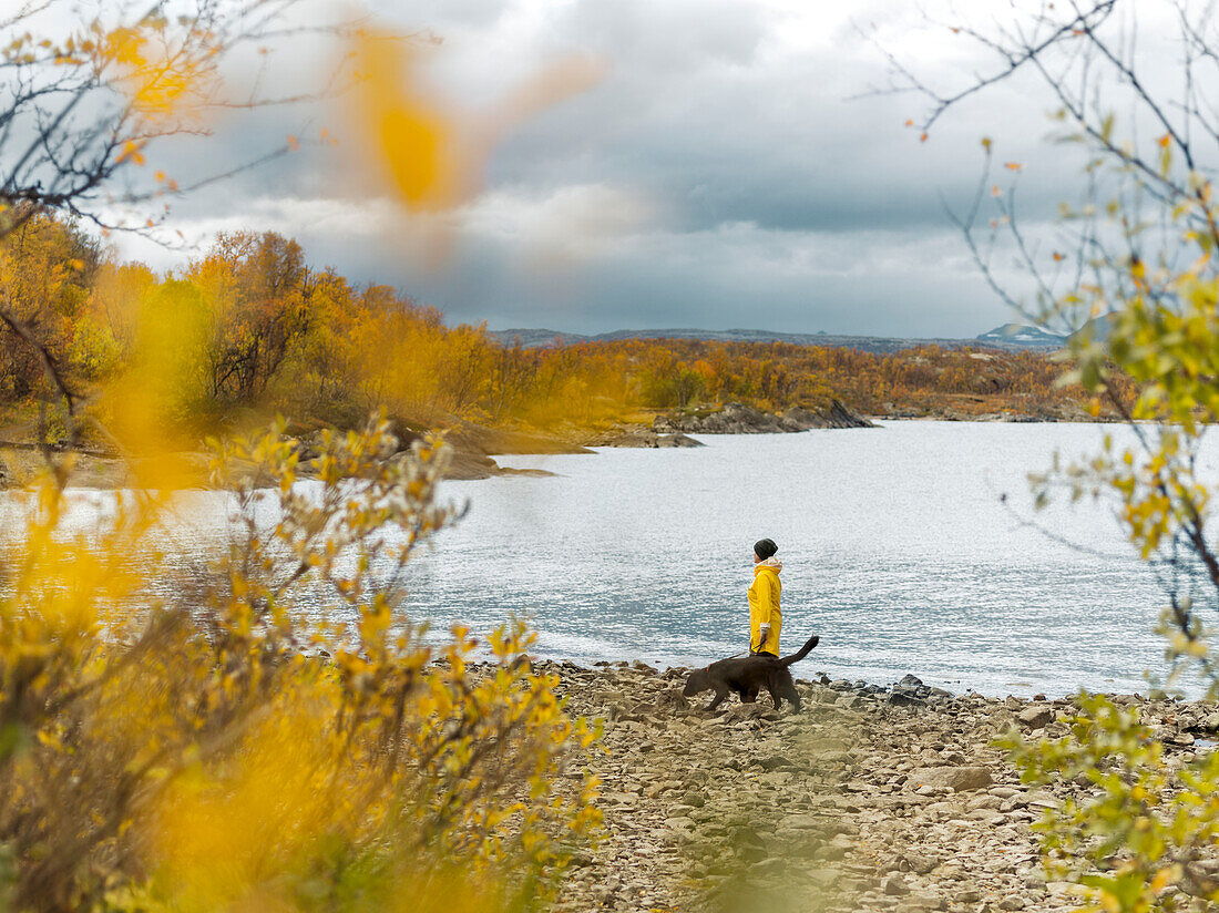 Woman and dog walking by river