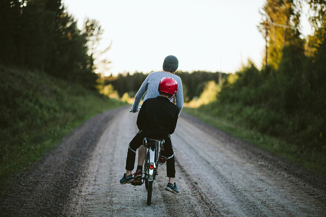 Boys riding bike on dirt track