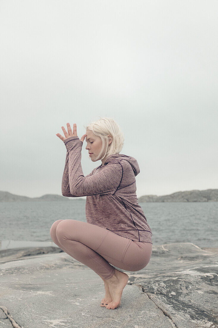 Junge Frau macht Yoga am See