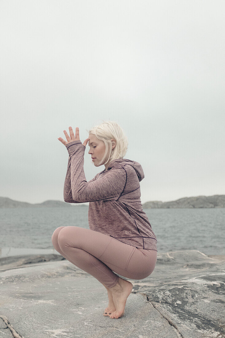 Young woman doing yoga by lake