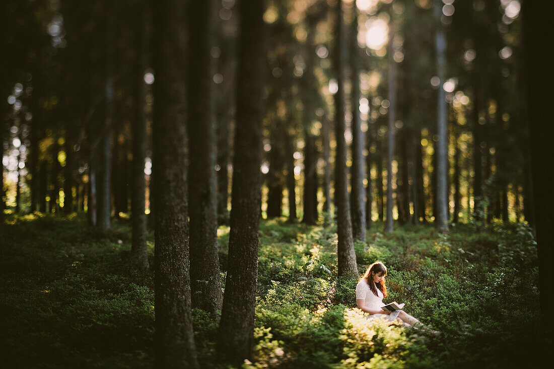 Frau sitzt im Wald