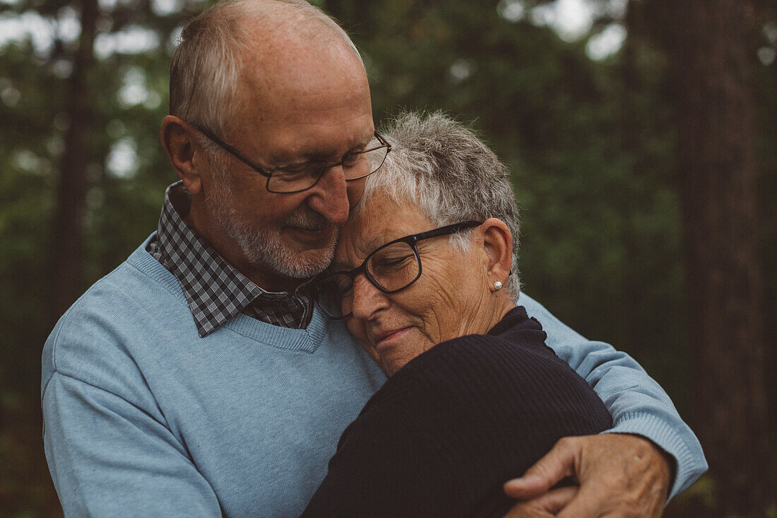 Older couple hugging in forest