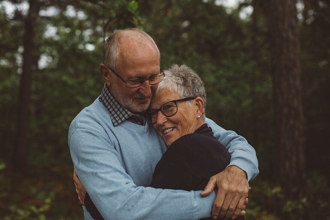 Older couple hugging in forest
